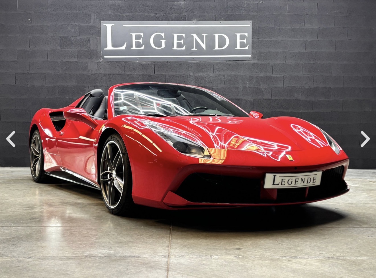 Ferrari 488 Spider rouge de trois quarts avant dans le showroom Légende